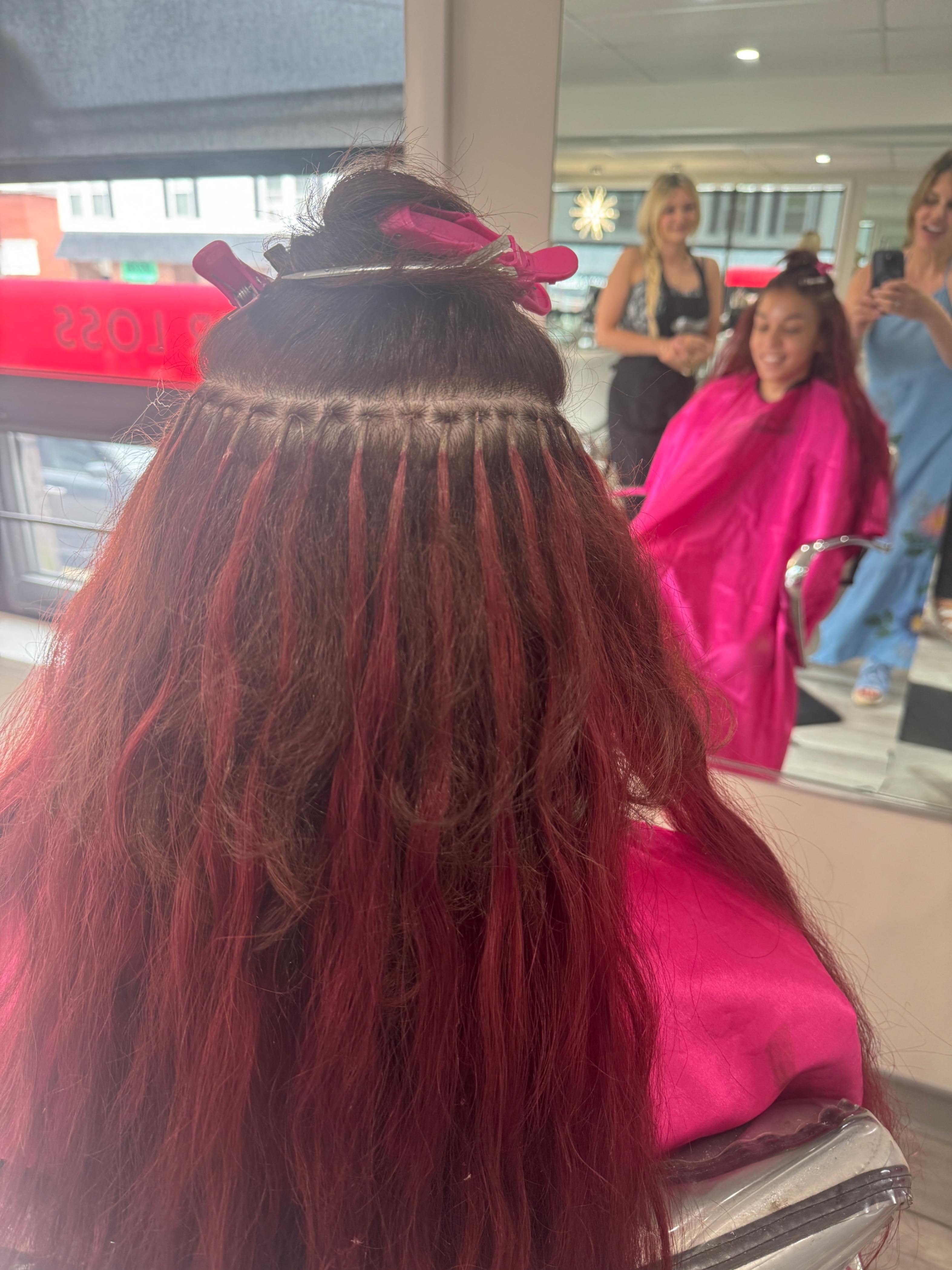 a stylist applying fusion hair extensions