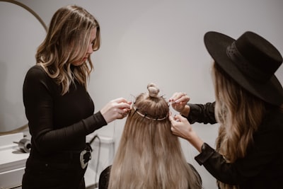 Professional hairstylists applying sew in extensions with beads
