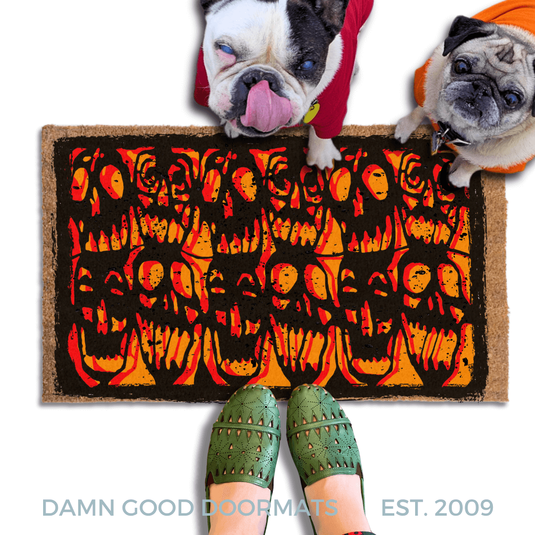 Gen X Halloween doormat with red, black and orange skulls stencil from 1985 cult film Desperately Seeking Susan on an outdoor doormat. Ppictured with a french bulldog and a fawn pug in Halloween hoodies  looking up at a person in green sandals