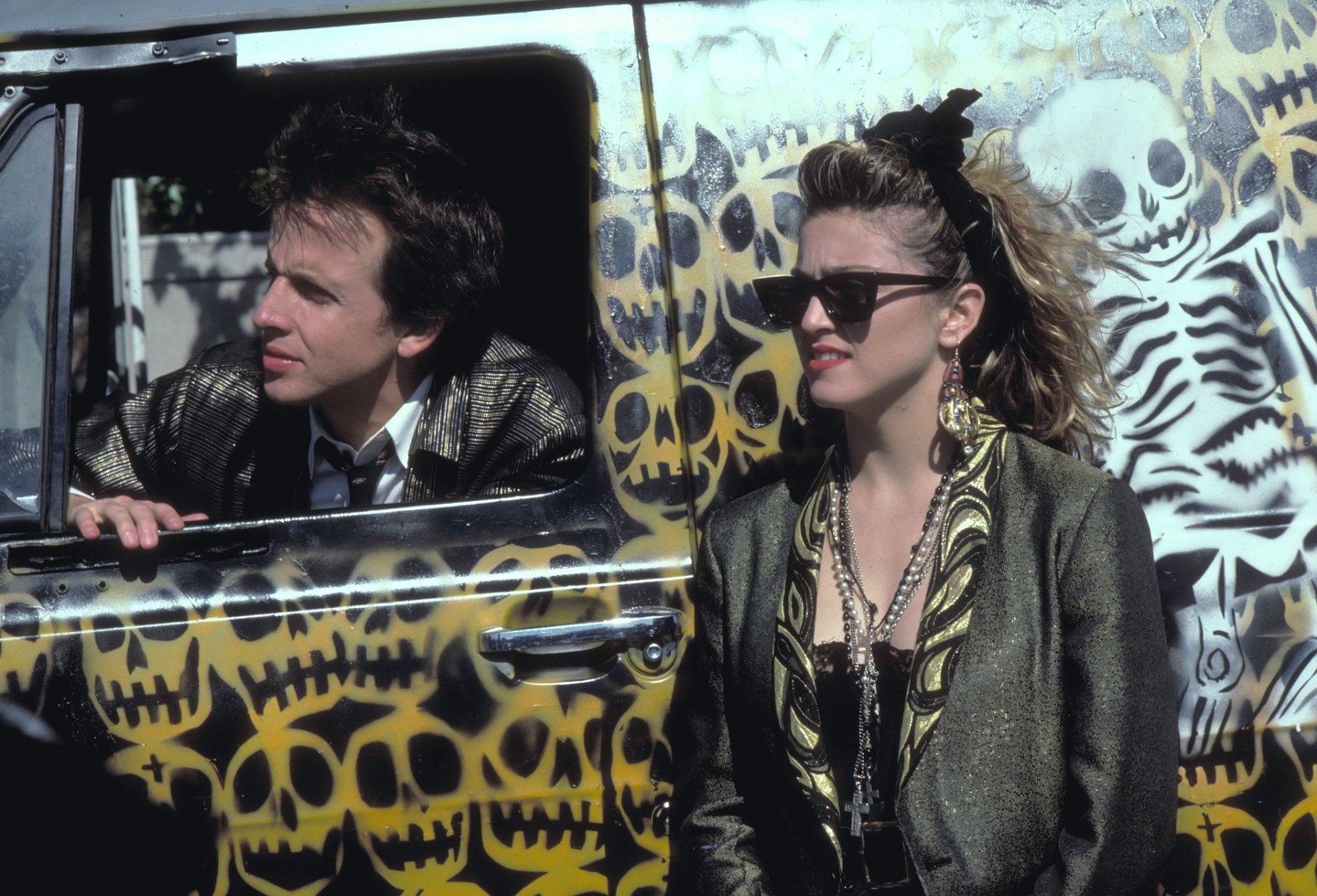Movie still from Gen X cult film "Desperately Seeking Susan" showing Madonna in front of a van stenciled with skulls