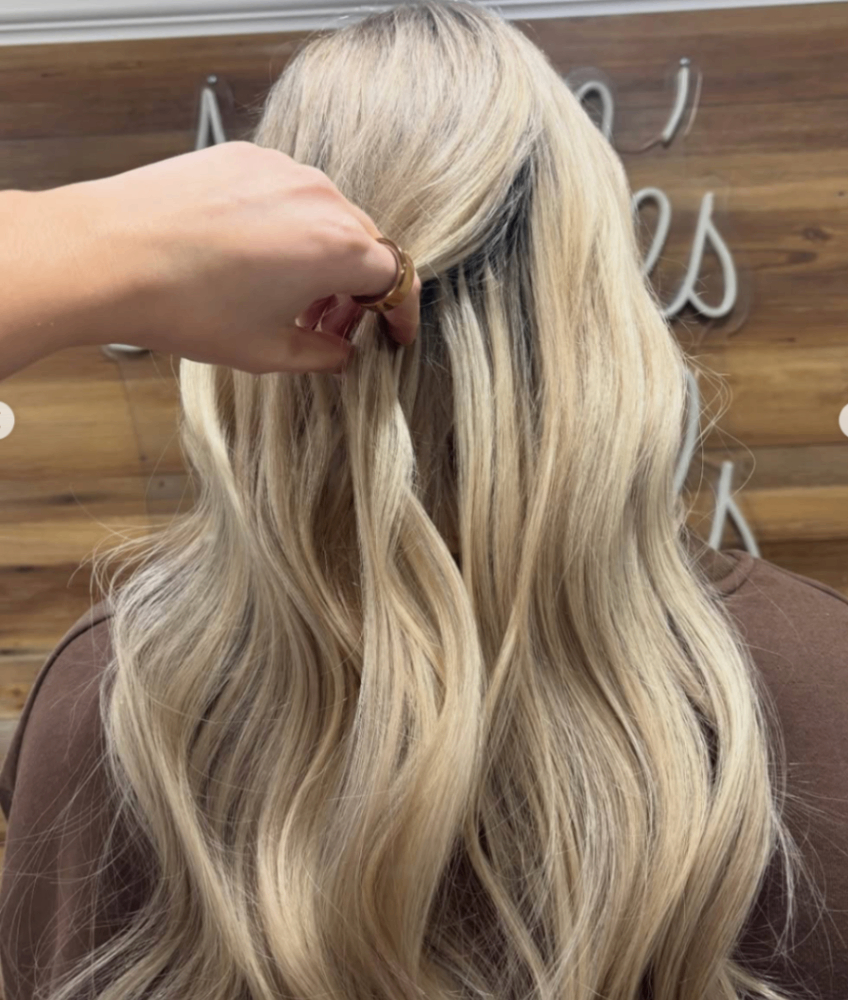 Stylist installing hair extensions during a private salon appointment.