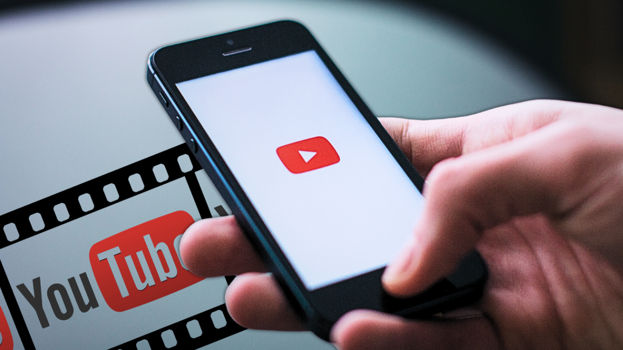 **Alt Text:** Person holding a smartphone with the YouTube app open, displaying the play button logo, in front of a screen showing a YouTube logo and filmstrip graphic. **Alt Text:** Person holding a smartphone with the YouTube app open, displaying the play button logo, in front of a screen showing a YouTube logo and filmstrip graphic.