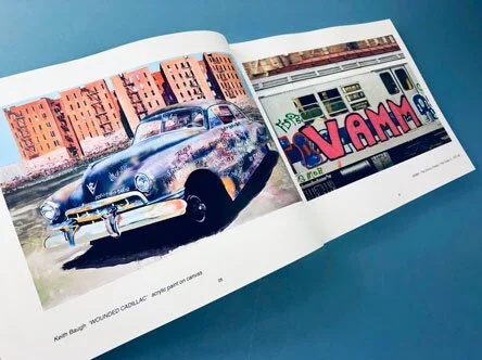 A spread from an art book featuring two vibrant artworks: one of a classic car with graffiti, and another of a train covered in bold street art, illustrating the creative use of daily prompts and drawing exercises.